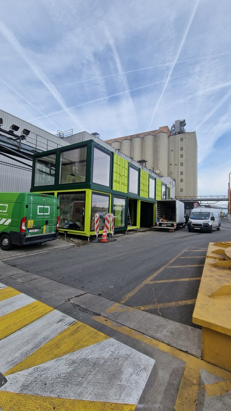 Gestapelde containerkantoren op schroefpalen in een havengebied