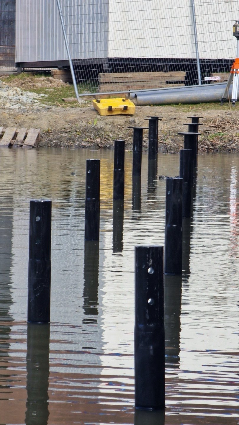 Gecoate schroefpalen staan rechtop in het water
